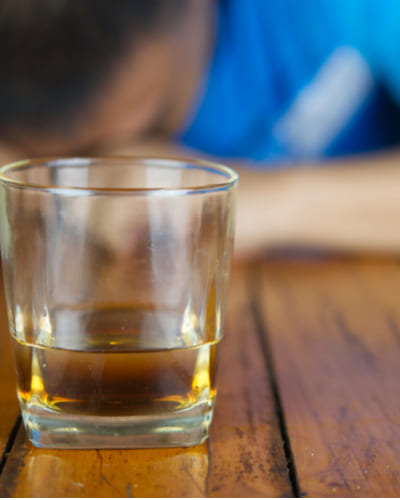 Стакан с алкоголем стоит напротив мужчины
